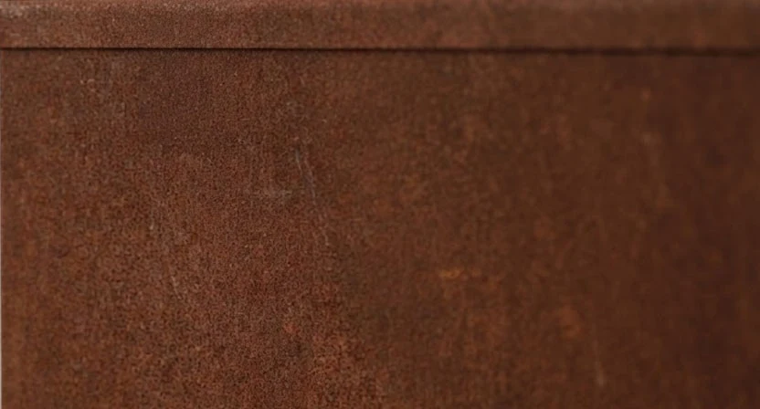 Nahaufnahme der geschlossenen rotbraunen Patina auf der Oberfläche eines Raumteilers aus Cortenstahl.